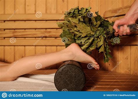 Young Woman Having A Russian Sauna Procedure With Bath Brooms From Oak