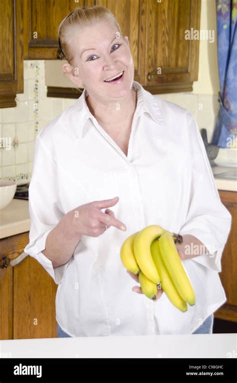 Housewife In Her Kitchen Shows With The Index Finger On A Few Bananas