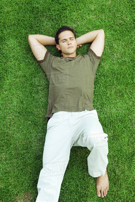 Young Man Lying On Grass With Eyes Closed High Angle View Stock