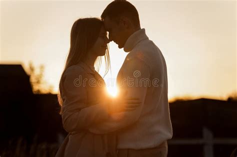 Silhouette Of Loving Couple Couple At Sunset Is Hugging And Touching