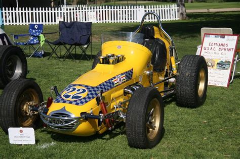 A Yellow Race Car Sitting On Top Of A Lush Green Field