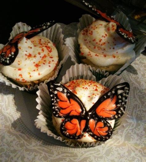 Three Cupcakes With White Frosting And Orange Butterflies On Them