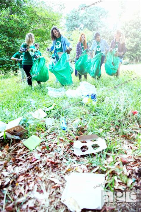 Environmentalist Volunteers Picking Up Trash In Field Stock Photo
