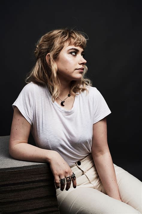 A Woman Sitting On Top Of A Wooden Table Wearing White Pants And A T Shirt