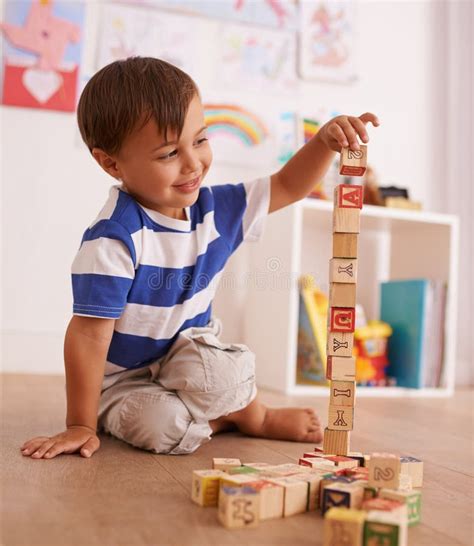 Make The Tower Bigger A Young Boy Playing With His Building Blocks In