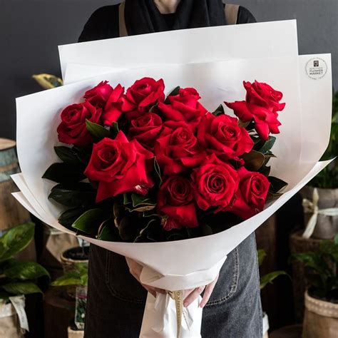 A Person Holding A Bouquet Of Red Roses