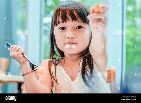 Little Asian Child Girl Having Breakfast At The Morning With A Happy