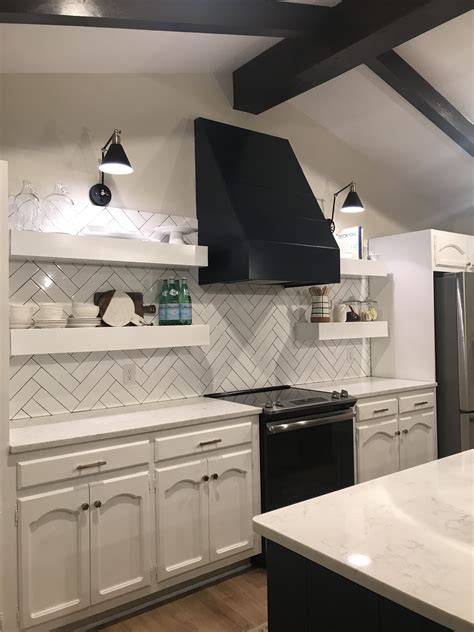 Blue and white beach style kitchen with herringbone backsplash tiles. Navy blue vent hood, herringbone backsplash, open shelving ...