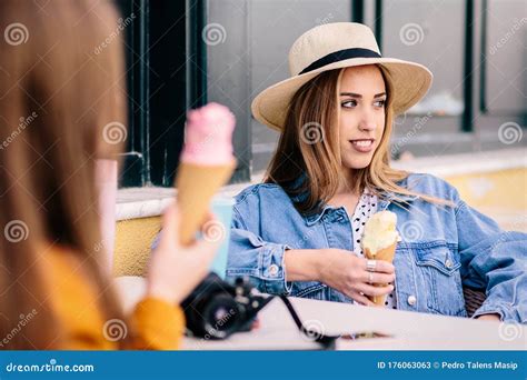 two girls enjoy a relaxed chat while having ice creams outdoors stock image image of blue