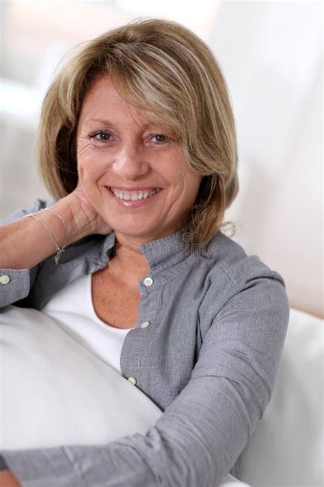Portrait Of Happy Smiling Senior Woman Sitting On Sofa Stock Photo