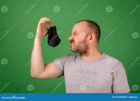 middle aged man sniffing smelly sock on green background laundry hygiene smelly feet concept