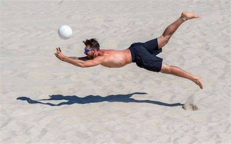 Человек без рубашки играет в волейбол на пляже Премиум Фото