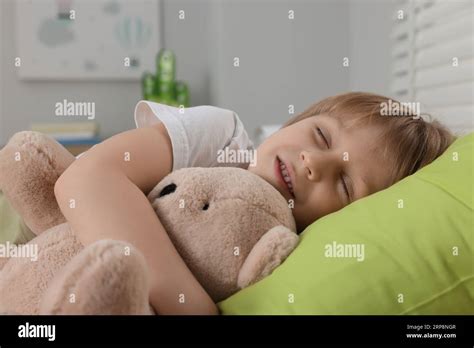 Little Boy Snoring While Sleeping With Teddy Bear In Bed At Home Stock