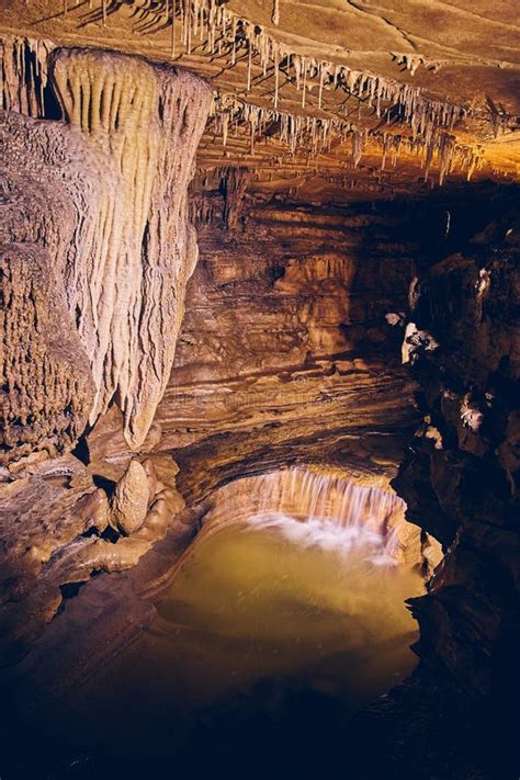 Waterfall In Underground Cave Next To Rock Formations Stalagmites And