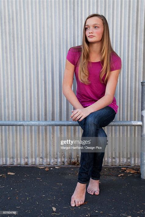 A Girl Sitting On A Metal Rail In Bare Feet Photo Getty Images