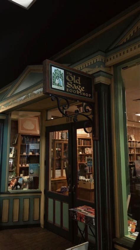 An Old Fashioned Store Front At Night With Lights On And Bookshelves In