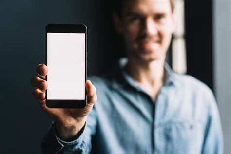 Blurred Young Man Showing Smartphone With Blank White Screen Photo