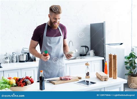 Handsome Smiling Bearded Man In Apron Cooking Delicious Steak Stock