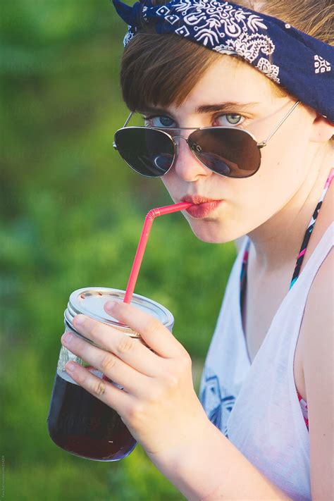 A Teen Looks Over Her Sunglasses While Sipping From A Straw By Stocksy Contributor Tana Teel