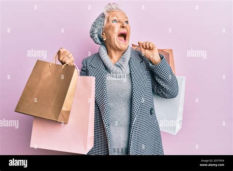 Senior Grey Haired Woman Holding Shopping Bags Angry And Mad Screaming