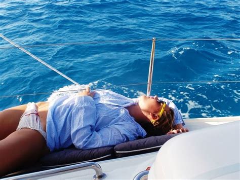 A Woman Laying Down On The Back Of A Boat In The Blue Water With Her