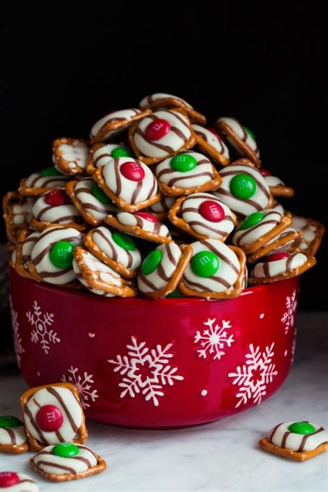 A Red Bowl Filled With White And Green Candy Covered Pretzel Cookies
