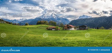 Idyllic Alpine Landscape With Green Meadows Farmhouses And Snowcapped