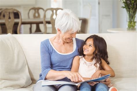 Grandmother And Granddaughter Interacting While Looking At Photo Album