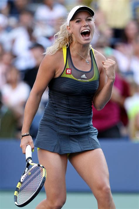 A Woman Holding A Tennis Racquet In Her Right Hand And Yelling Into The Air