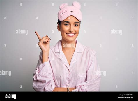 Young Beautiful Brunette Woman Wearing Pajama And Sleep Mask Over White Background With A Big