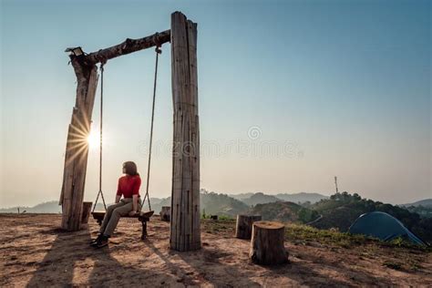 Loneliness Woman Sitting On The Swing And Looking At The Sun At Sunset