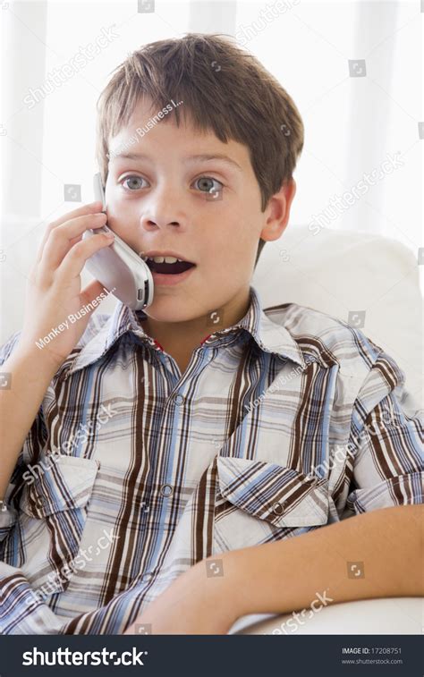 Young Boy Sitting On A Sofa Talking On A Mobile Phone Stock Photo
