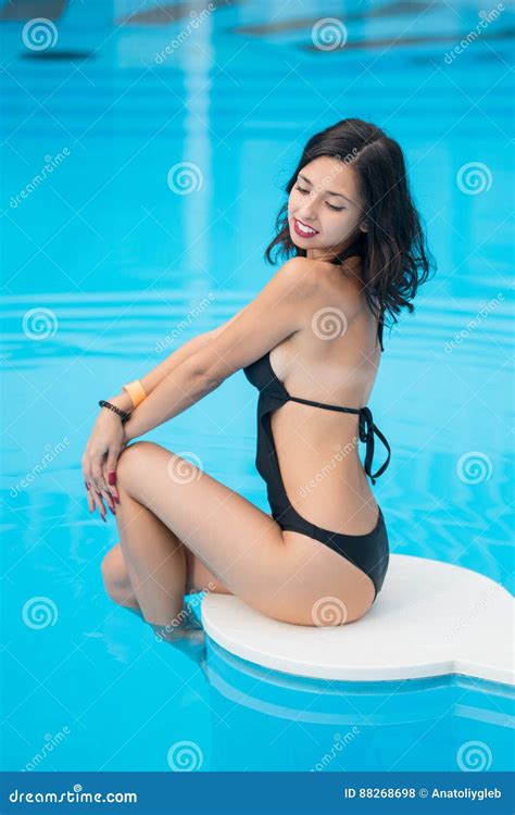 Tender Woman In Black Swimsuit With Shapely Body Sitting Near The