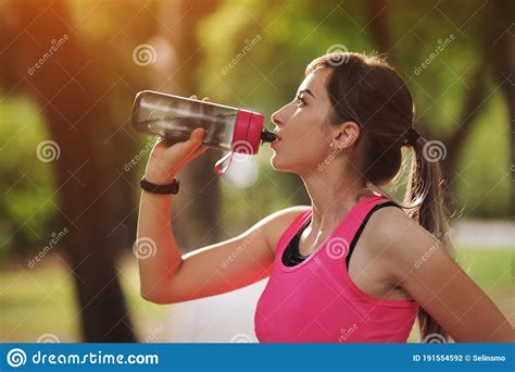 Beautiful Fitness Athlete Runner Woman Drinking Water In The Park
