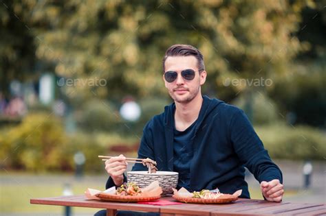 Young Man Eating Take Away Noodles On The Street Stock Photo By