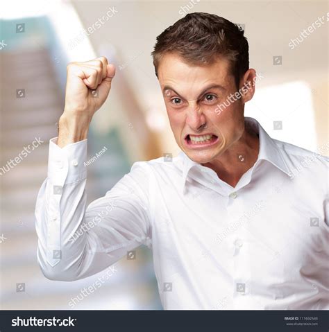 Portrait Of Angry Young Man Clenching His Fist Indoor Stock Photo