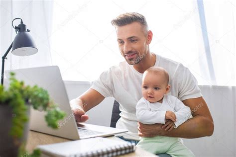 Padre Sonriente Sentado En El Escritorio De La Computadora En Casa Y