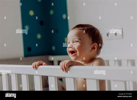 Baby Boy Standing In His Cot Laughing Stock Photo Alamy
