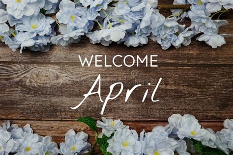 Welcome April Text And Blue Flower Decoration On Wooden Background
