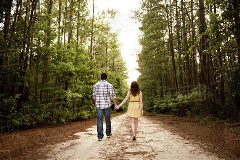 Couple Holding Hands And Walking On Forest Road Stock Photo Dissolve