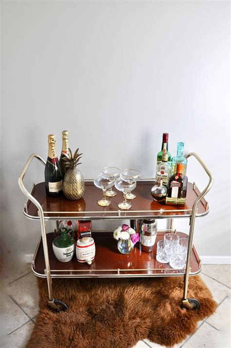 This butler bar cart set has trays made of mirrored glass with beveled edges, which exudes art deco glamor and shines on side tables that make hosting impromptu drinks and snacks simple. Vintage long decadent mid century modern brown and gold ...
