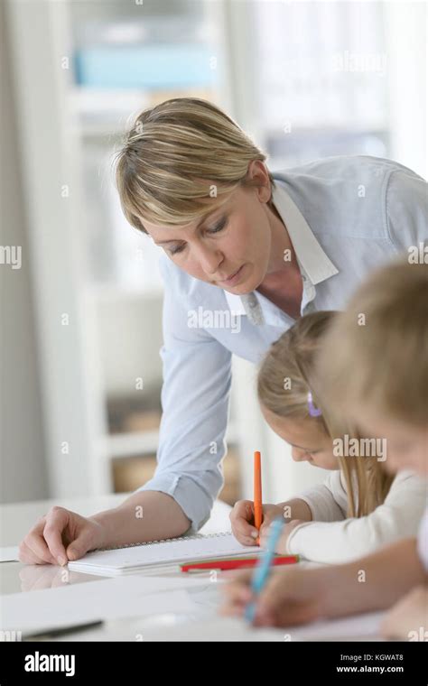 Teacher Helping Kids In Classroom Stock Photo Alamy