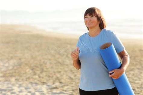 Smiling Middle Aged Woman Running On The Beach On Sunrise 40s Or 50s