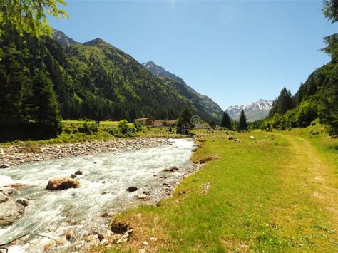 Landscape Shot Of A Stream Flowing Water Surrounded By Green Mountains