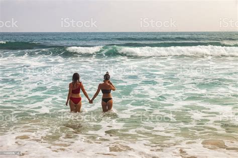 rear view lesbian couple women holding hands on beach at tropical ocean background lifestyle two