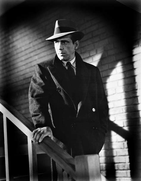 A Man In A Suit And Hat Leaning On A Rail With His Hand On The Railing