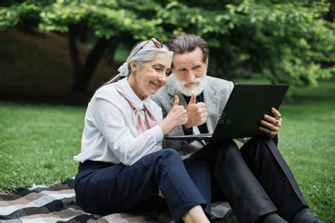 Happy Mature Couple Using Laptop For Video Call At Park Stock Image