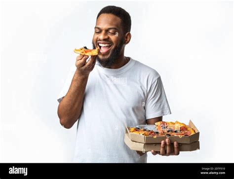 Hungry Black Guy Eating Pizza Holding Box Standing In Studio Stock Photo Alamy
