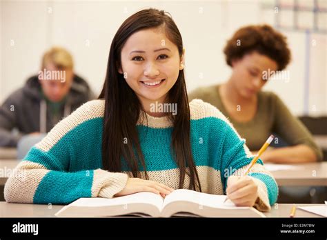 Female High School Student Studying At Desk In Classroom Stock Photo