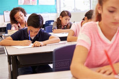 Elementary School Kids Working At Their Desks In A Classroom Stock